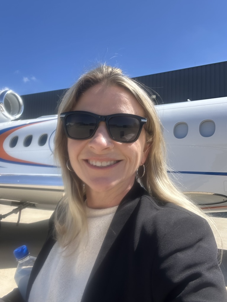 Randi Jo standing professionally beside a private aircraft